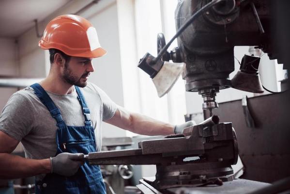 experienced-operator-in-a-hard-hat-metalworking-industry-concept-professional-engineer-metalworker-operating-cnc-milling-machine-center-in-manufacturing-workshop-photo